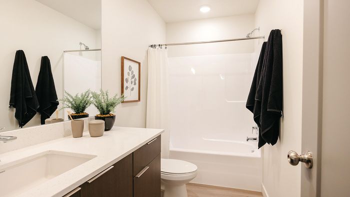 Modern bathroom at RailRunner townhomes featuring clean finishes, a tub shower, and bright, neutral design.