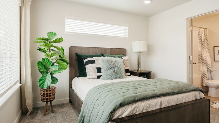 Spacious bedroom at RailRunner townhomes with natural light, neutral tones, and an attached bathroom.