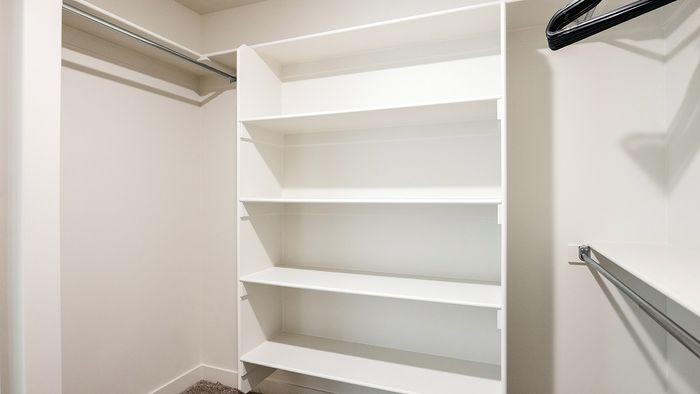 Walk-in closet at RailRunner townhomes featuring built-in shelving and hanging space.