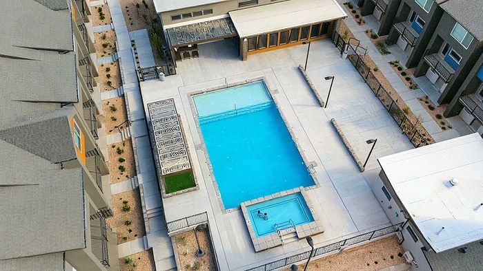 Aerial view of the pool and hot tub at RailRunner townhomes with surrounding deck space and modern community layout.
