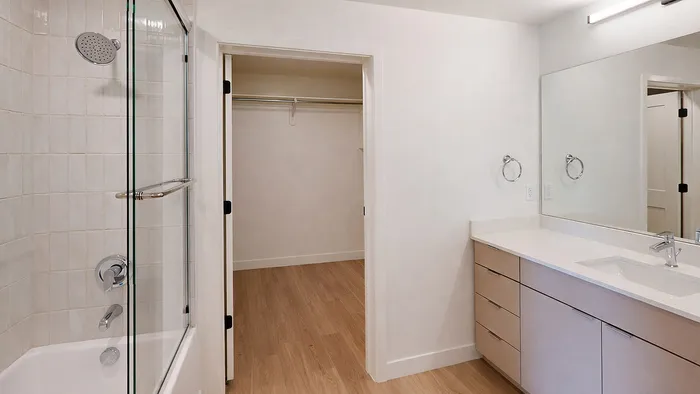 Modern bathroom with glass shower and walk-in closet in Aster two-bedroom apartment at Silo Park