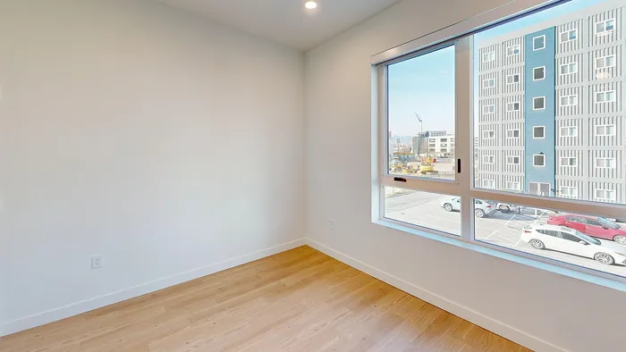 Bright studio living area with large window and wood flooring in Bluebell floor plan at Silo Park