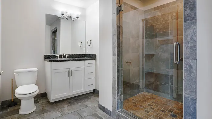 Modern bathroom at Junction View Apartments featuring walk-in glass shower, vanity, and contemporary finishes.