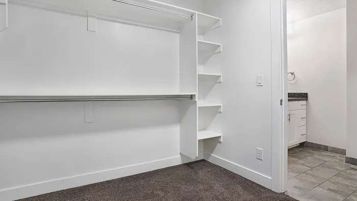 Walk-in closet at Junction View Apartments featuring built-in shelving, hanging space, and organized storage.