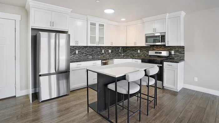 Modern kitchen at Junction View Apartments featuring stainless steel appliances, white cabinets, and center island.