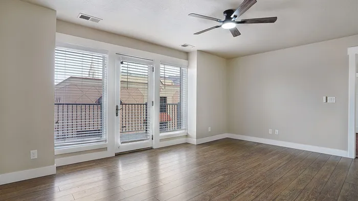Living room at Junction View Apartments featuring wood flooring, balcony access, and large windows.
