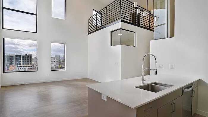 Double-height living area with kitchen island in a Greenside penthouse apartment at Silo Park
