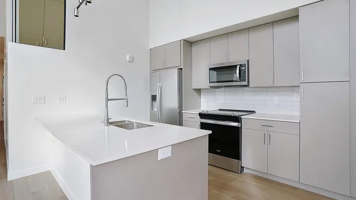 Modern penthouse kitchen with island and stainless steel appliances at Greenside