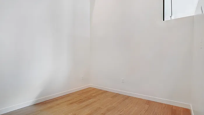 Second bedroom in a Greenside penthouse with natural light and wood flooring