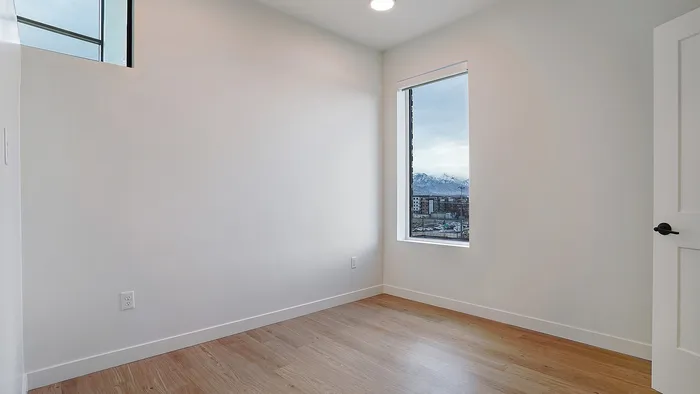 Primary bedroom in a Greenside penthouse with large window and wood flooring