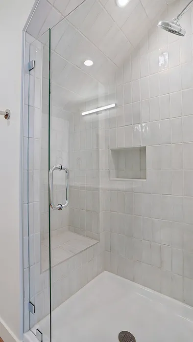 Glass-enclosed shower with tiled walls in a Greenside penthouse bathroom