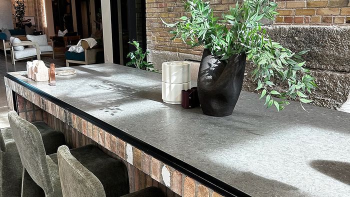 Community workspace with a long concrete table, seating, and exposed brick inside Bissinger & Co.