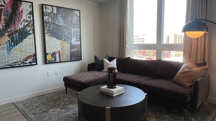 Contemporary living room with oversized windows, modern furnishings, and city views.