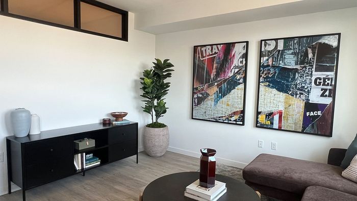 Open-concept apartment living room with modern d&eacute;cor, artwork, and contemporary finishes.