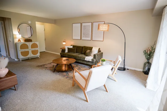 Inviting living room with modern decor, featuring a cozy green sofa, stylish round coffee table, and elegant light fixtures, perfect for relaxation.