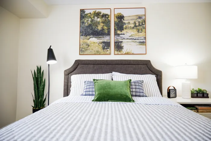 Inviting bedroom with a plush bed, modern decor, and serene artwork, creating a cozy and stylish atmosphere.