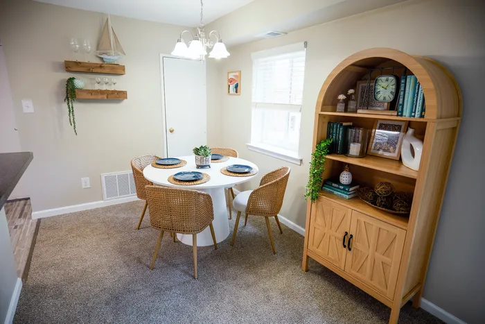 Cozy dining area with a round table, chic rattan chairs, and elegant decor, perfect for intimate gatherings.