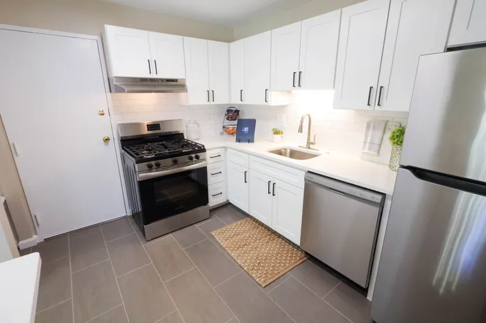 Modern kitchen with sleek stainless steel appliances, bright white cabinetry, and stylish tile backsplash.