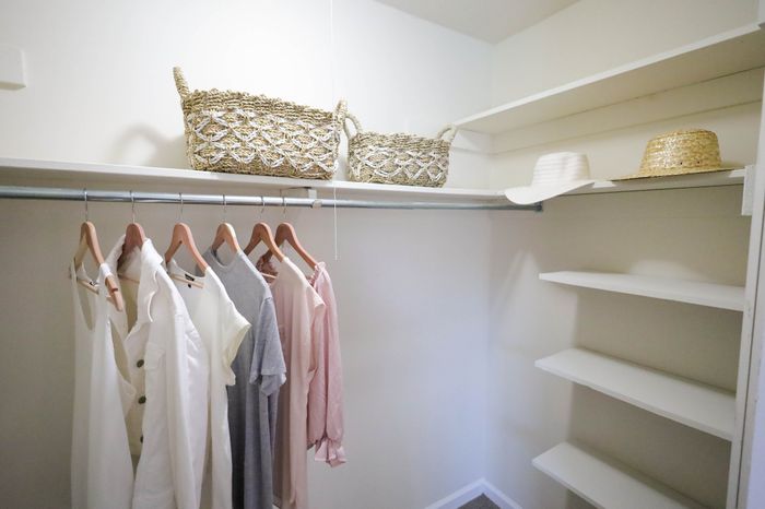Spacious walk-in closet with stylish wooden hangers, woven baskets, and well-organized shelving.