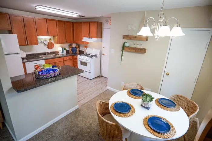 Charming kitchen and dining area with warm wooden cabinets, sleek countertops, and cozy dining table setup highlighted by elegant lighting.