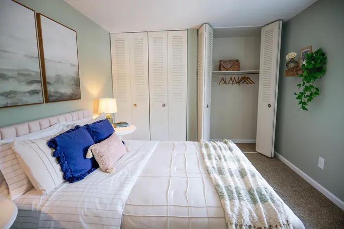Charming bedroom with plush bedding, stylish decor, and an open closet in a serene green setting.