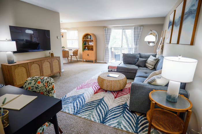 Inviting living room with modern decor, featuring a cozy gray sectional sofa, vibrant patterned rug, and a large flat-screen TV, perfect for relaxation and entertaining.