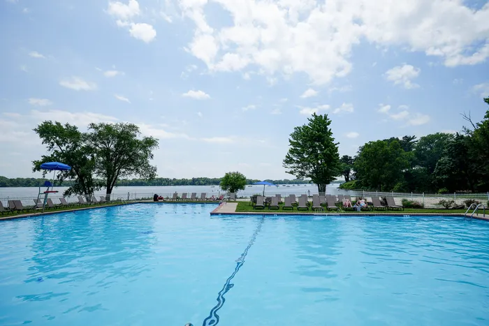 Inviting outdoor pool with a stunning lake view, surrounded by comfortable lounge chairs and lush greenery.