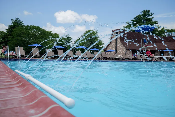 Inviting outdoor pool with elegant fountains, surrounded by relaxing deck chairs and vibrant umbrellas, perfect for soaking up the sun.