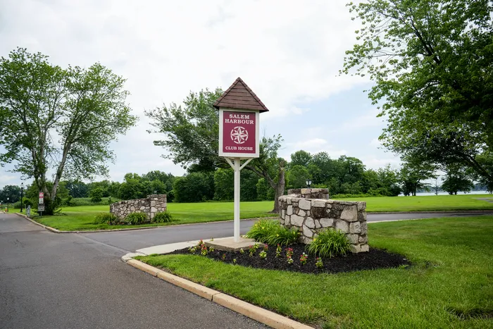 Charming entrance to Salem Harbour Club House surrounded by lush green lawns and vibrant landscaping, offering a serene and inviting atmosphere.