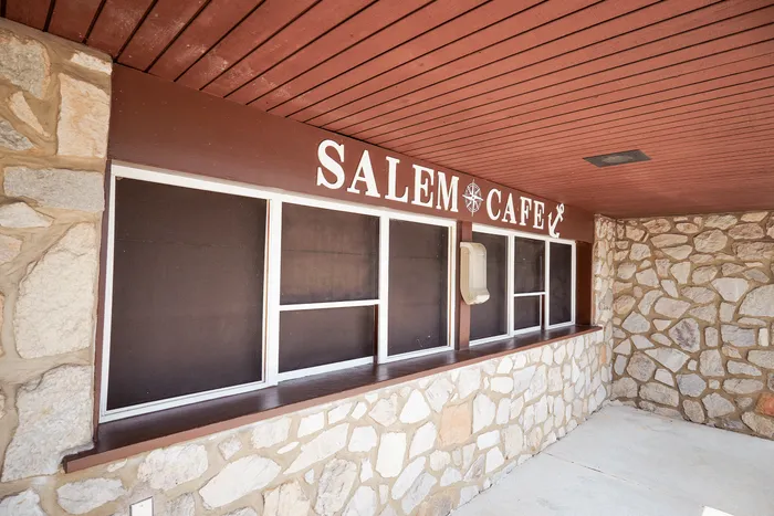 Charming exterior of a rustic stone-walled cafe with inviting wooden accents and a cozy atmosphere.