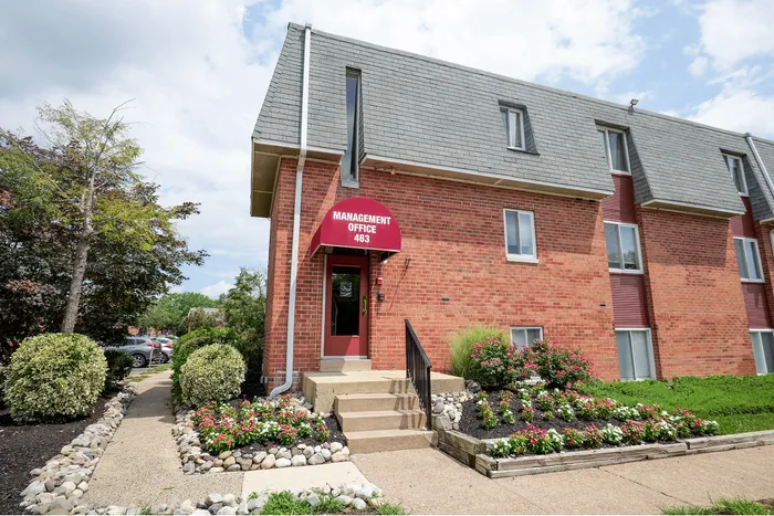 Charming brick management office with lush landscaping and inviting entrance, perfect for a welcoming community atmosphere.