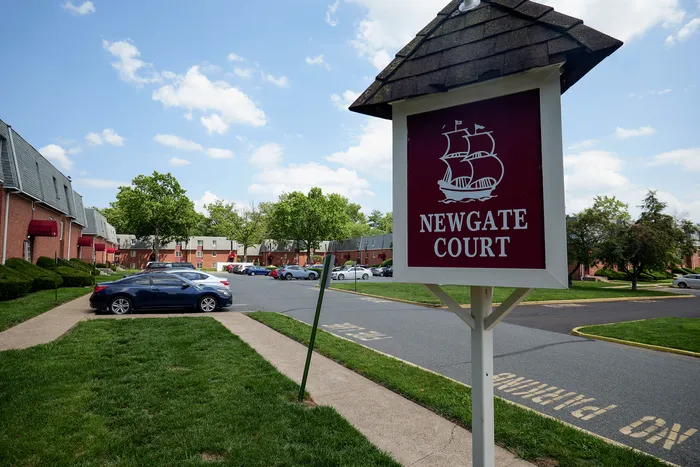 Inviting Newgate Court entrance with scenic landscaping and modern brick buildings under a bright blue sky.
