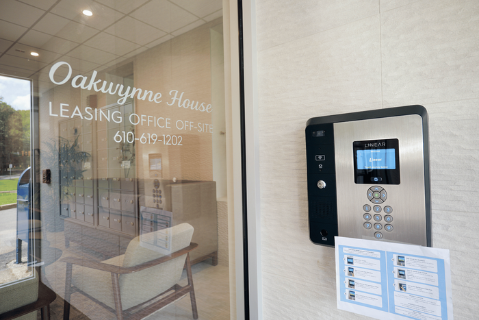 Modern entrance to Oakwynne House with a sleek, high-tech intercom system and inviting lobby glimpsed through glass doors.