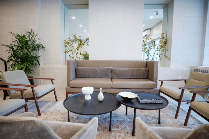 Elegant contemporary living space with a chic beige sofa, stylish armchairs, and modern decor including unique coffee tables and lush green plants.