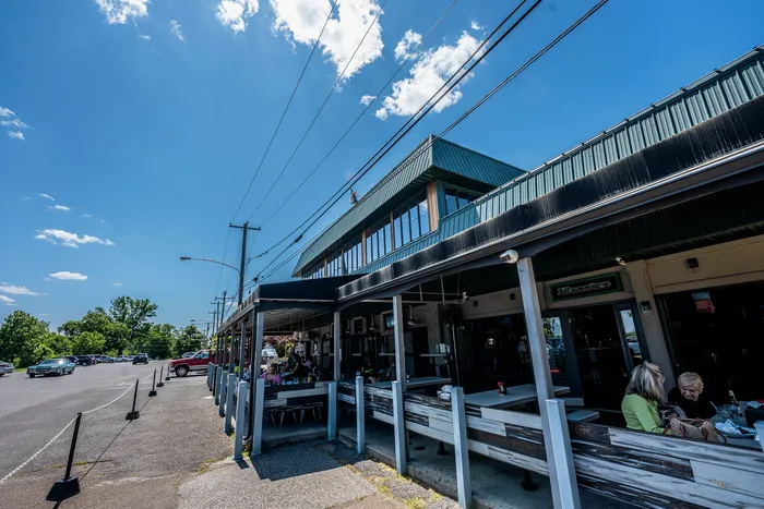 Sunlit outdoor dining area at a charming restaurant with clear blue skies, bustling atmosphere, and inviting seating.