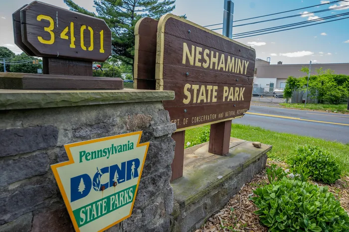 Welcoming rustic sign at Neshaminy State Park, surrounded by lush greenery, showcasing a picturesque entrance in Pennsylvania.