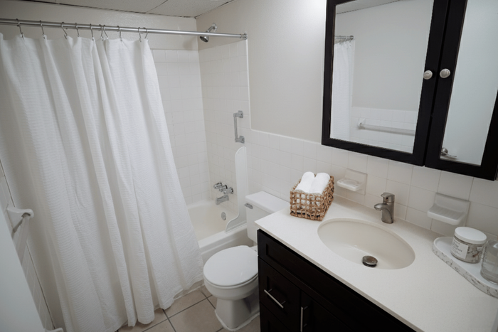 Elegant bathroom with a modern design featuring a sleek vanity, mirrored cabinet, and pristine white shower curtain.