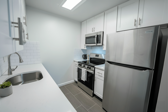 Sleek modern kitchen with stainless steel appliances, white cabinetry, and elegant subway tile backsplash, offering a fresh and bright culinary space.