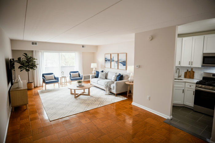Bright and inviting living room with elegant hardwood floors, modern furnishings, and a stylish open kitchen.