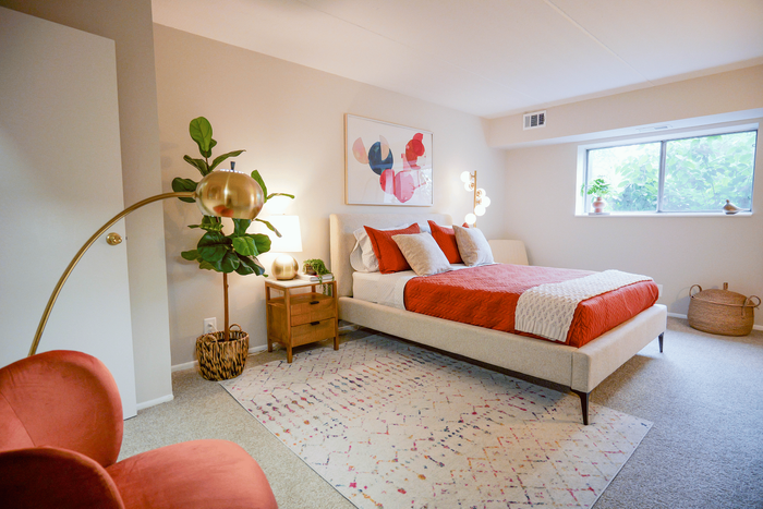 Inviting bedroom with vibrant decor, featuring a plush bed, stylish artwork, and a cozy reading chair by the window.