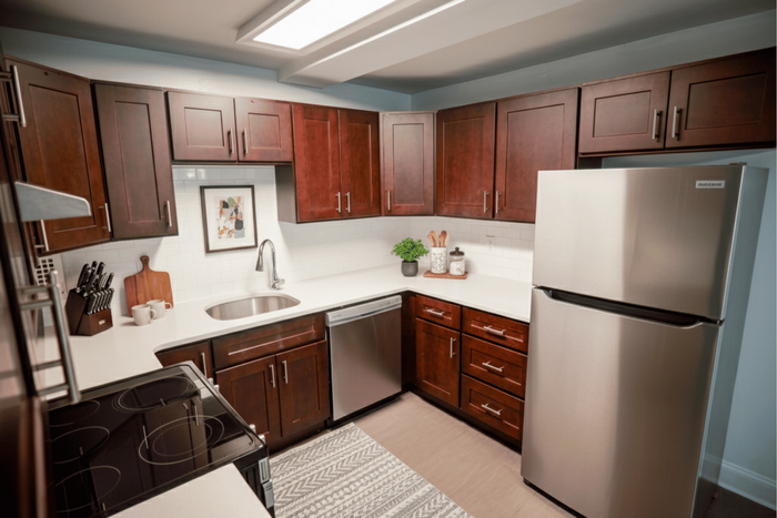 Modern kitchen with sleek stainless steel appliances, rich wooden cabinetry, and elegant white countertops.