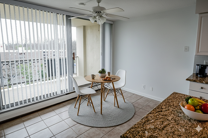Bright and inviting dining area with cozy seating for two, modern decor, and a scenic view through large sliding glass doors.