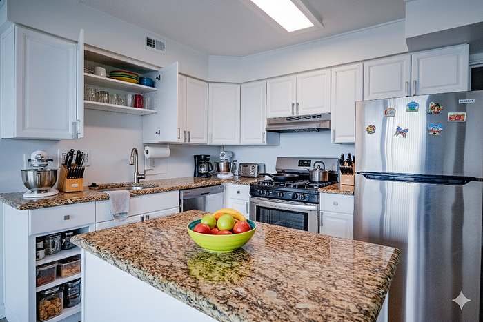 Modern kitchen with sleek stainless steel appliances, granite countertops, and elegant white cabinetry, perfect for culinary enthusiasts.