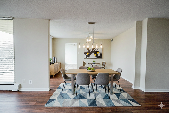 Elegant dining area with modern chandelier, stylish wooden table, and comfortable grey chairs on a geometric rug, offering a perfect blend of sophistication and warmth.