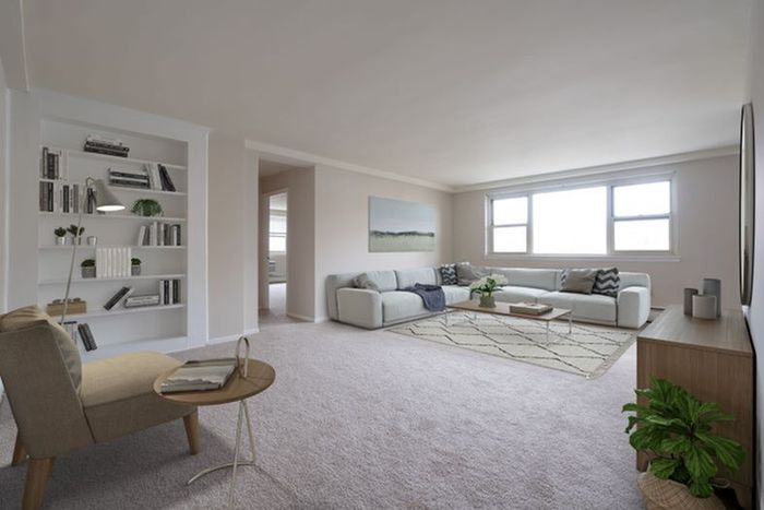 Bright and inviting living room with a modern sofa, stylish bookshelf, and large windows offering plenty of natural light.