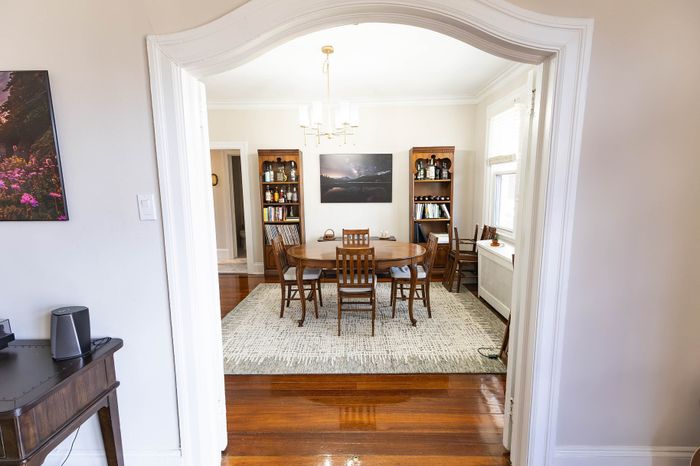 Elegant dining room with polished hardwood floors, a classic wooden table, and built-in bookcases, creating a warm and inviting space.