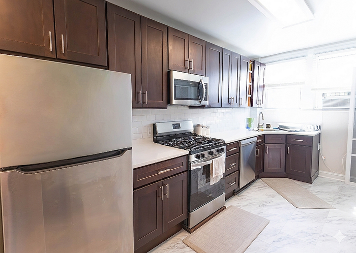 Modern kitchen with sleek stainless steel appliances, elegant dark wood cabinets, and bright natural lighting.