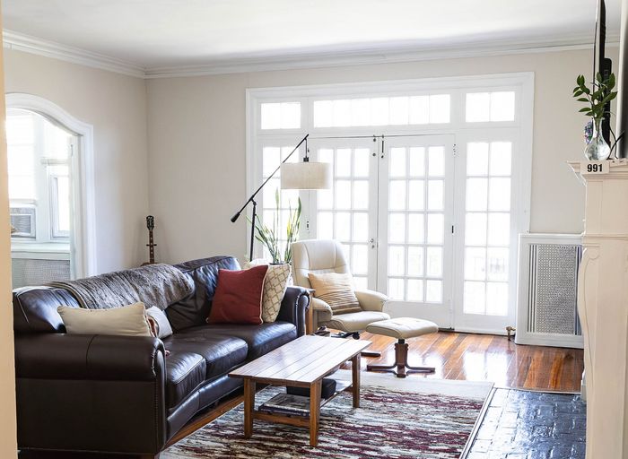 Bright and inviting living room with large windows, cozy leather sofa, stylish armchair, and elegant decor.