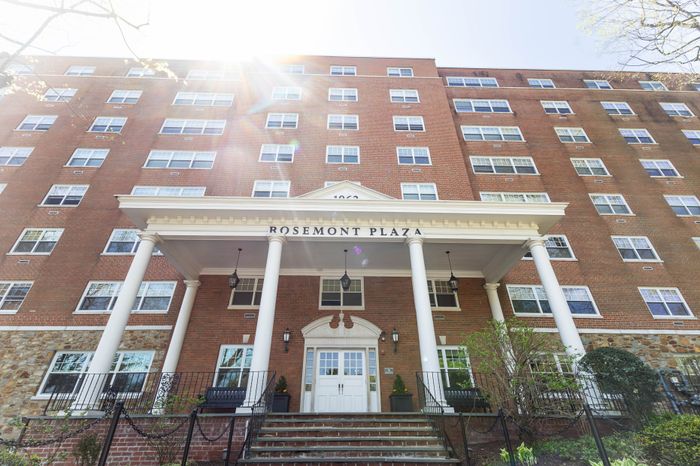 Charming brick exterior of Rosemont Plaza with elegant white columns and lush landscaping, inviting entrance for modern living.