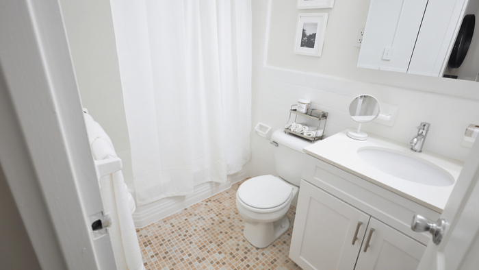 Elegantly designed bathroom featuring chic white fixtures, modern vanity, and warm mosaic tile flooring for a luxurious touch.